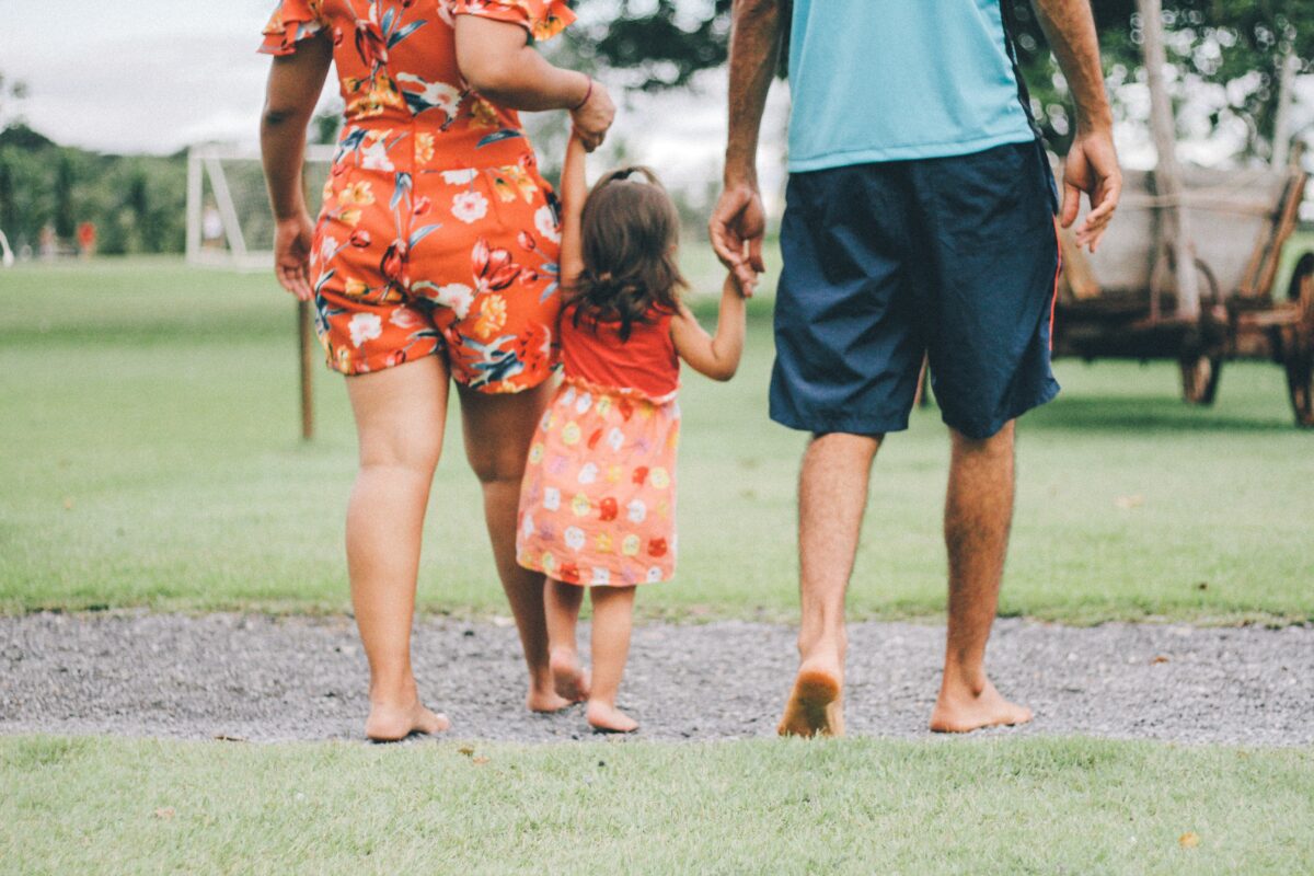 Child holding her parents' hands.