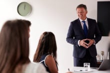 Mature,Businessman,Addressing,Group,Meeting,Around,Table,At,Graduate,Recruitment