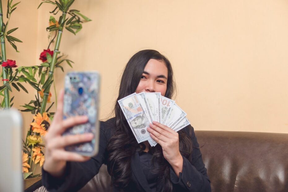 young woman holding money taking a selfie