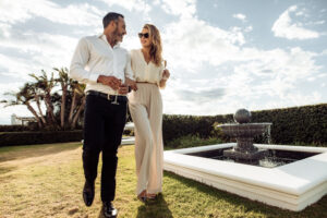 Stylish wealthy couple walking on a lawn with champagne