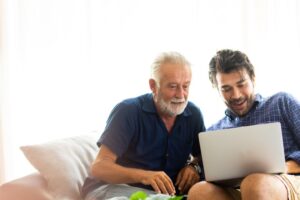 Millennial-age son showing older dad something on a laptop