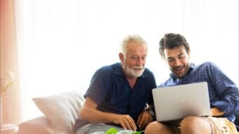 Millennial-age son showing older dad something on a laptop