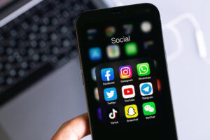 Showing social media mobile apps (Facebook, Instagram, WhatsApp, Twitter, YouTube, Telegram, TikTok, Snapchat) on screen macro interface smartphone iPhone in hand.
