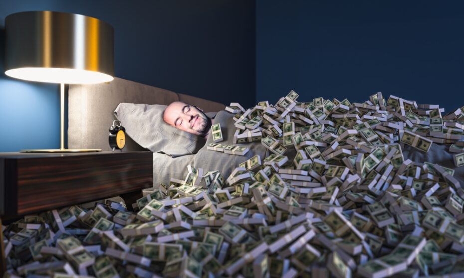 Man sleeping in a bed covered with lots of money