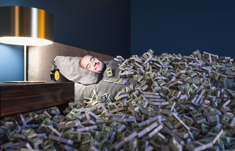 Man sleeping in a bed covered with lots of money