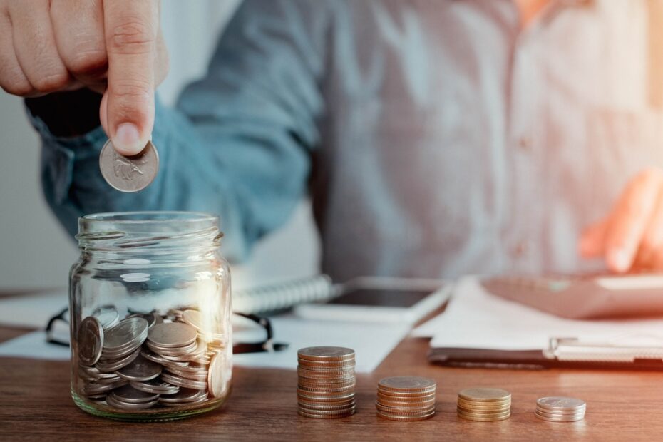 Man looking at bills and putting quarters in a jar to save