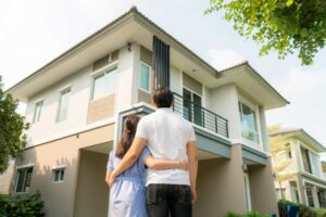 Couple standing in front of home they just paid off