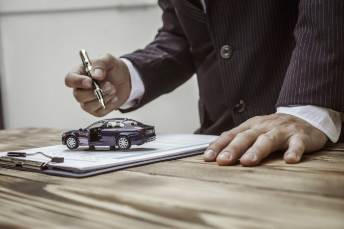 A businessman in a formal suit signs a contract, hands close up, highlighting financial terms like amortization, APR, and asset management, documents symbolizing various loan and insurance concepts.