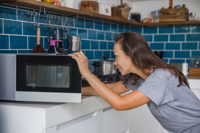 Woman putting food into her microwave