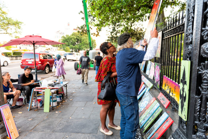 New Orleans, USA - April 22, 2018: Art exhibition on Decatur street, art seller vendor selling paintings drawing with people walking on sidewalk