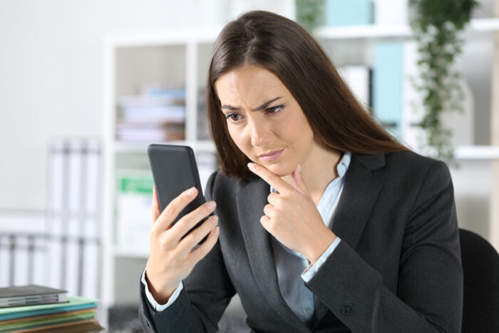 Suspicious executive checking smart phone at office