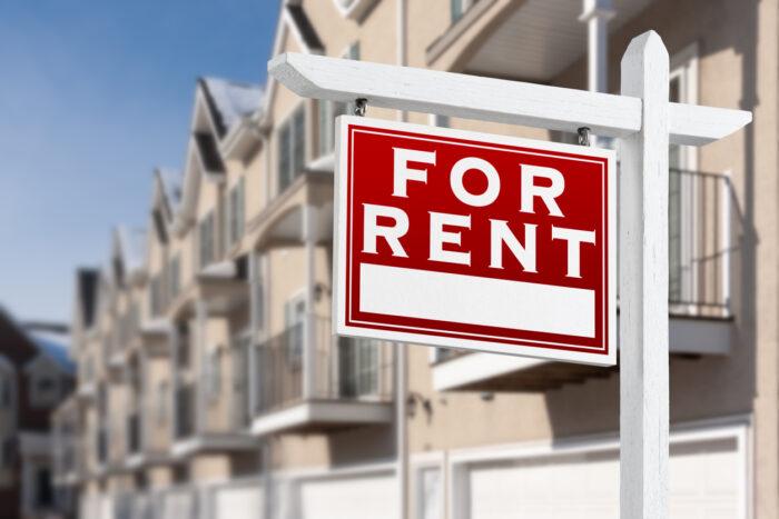 For Rent Real Estate Sign In Front of a Row of Apartment 