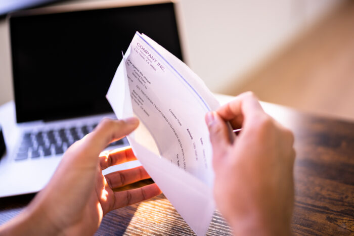 Payroll Cheque In Envelope. Man Hand Holding Paycheck