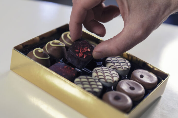 Close up of a person taking a chocolate truffle from a box.