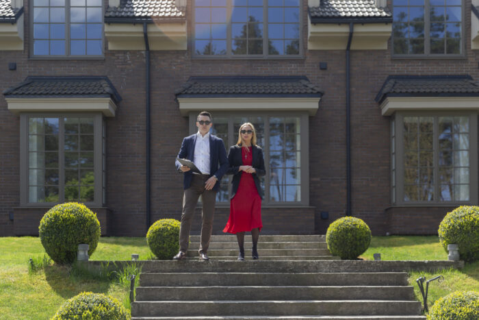 Couple of professional property agents on steps by residence