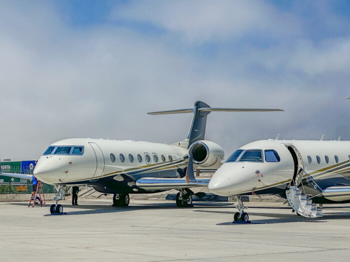 2 White Blue and Gold Private Jets Parked on a Runway.