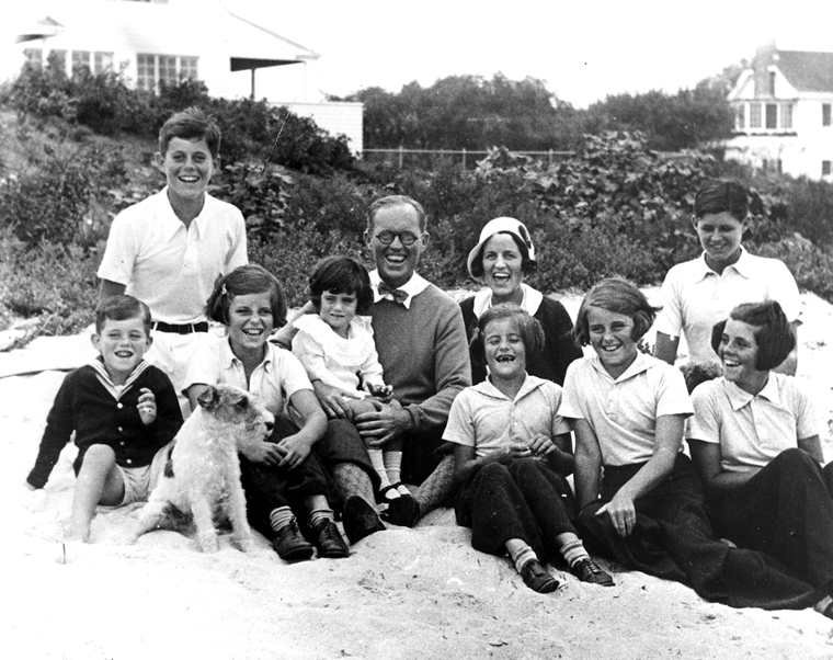 PC 8  The Kennedy Family at Hyannis Port, 1931. L-R: Robert Kennedy, John F. Kennedy, Eunice Kennedy, Jean Kennedy (on lap of) Joseph P. Kennedy Sr., Rose Fitzgerald Kennedy (behind) Patricia Kennedy, Kathleen Kennedy, Joseph P. Kennedy Jr. (behind) Rosemary Kennedy. Dog in foreground is "Buddy". Photograph by Richard Sears in the John F. Kennedy Presidential Library and Museum, Boston.