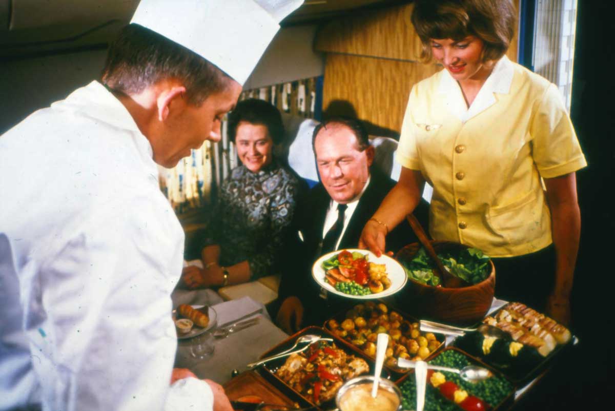 Passengers being served a delicious meal in the 1970s on a plane