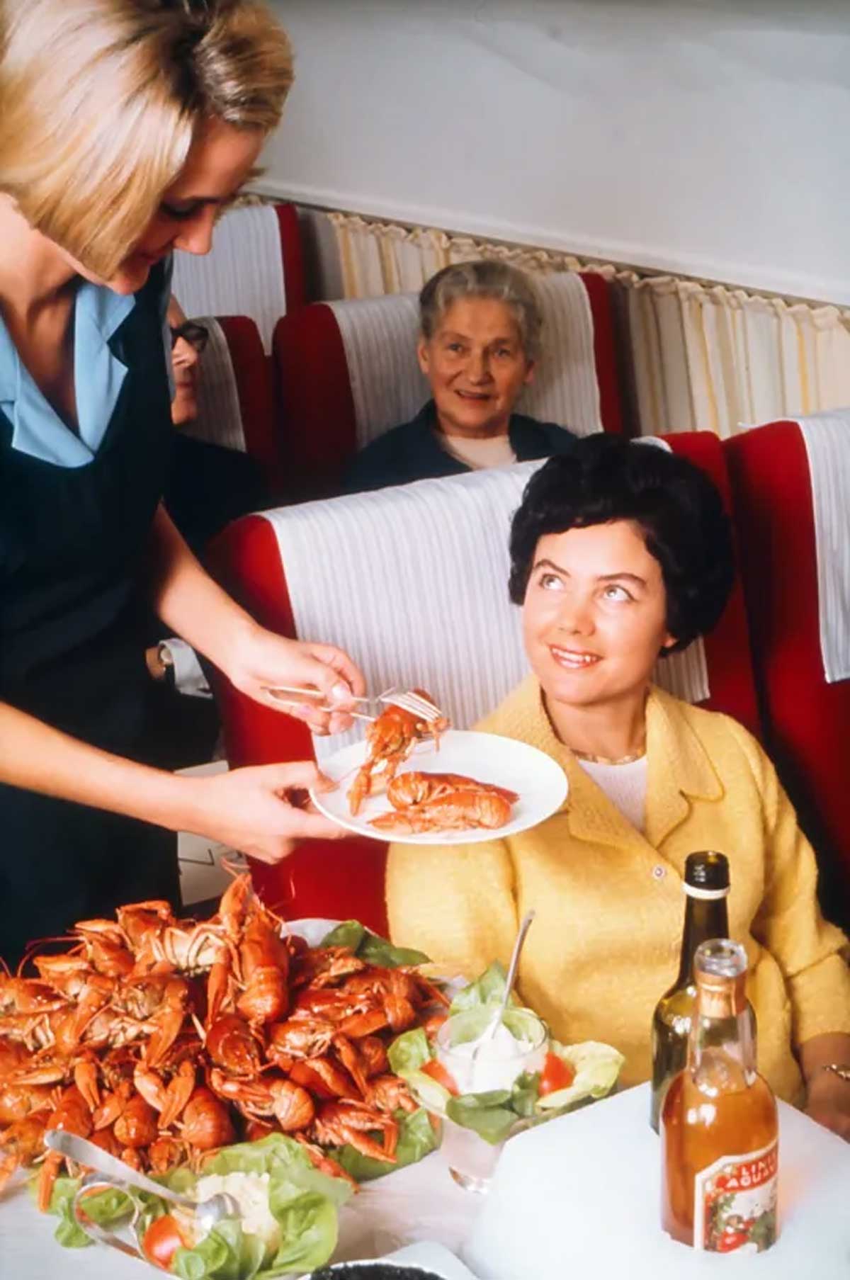 Woman being served lobster on a flight in the 70s