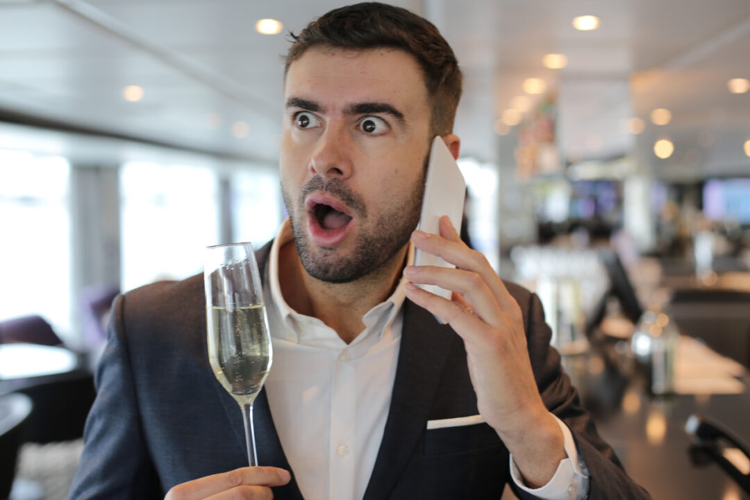 Attractive elegant man shocked while making a call from luxurious bar.