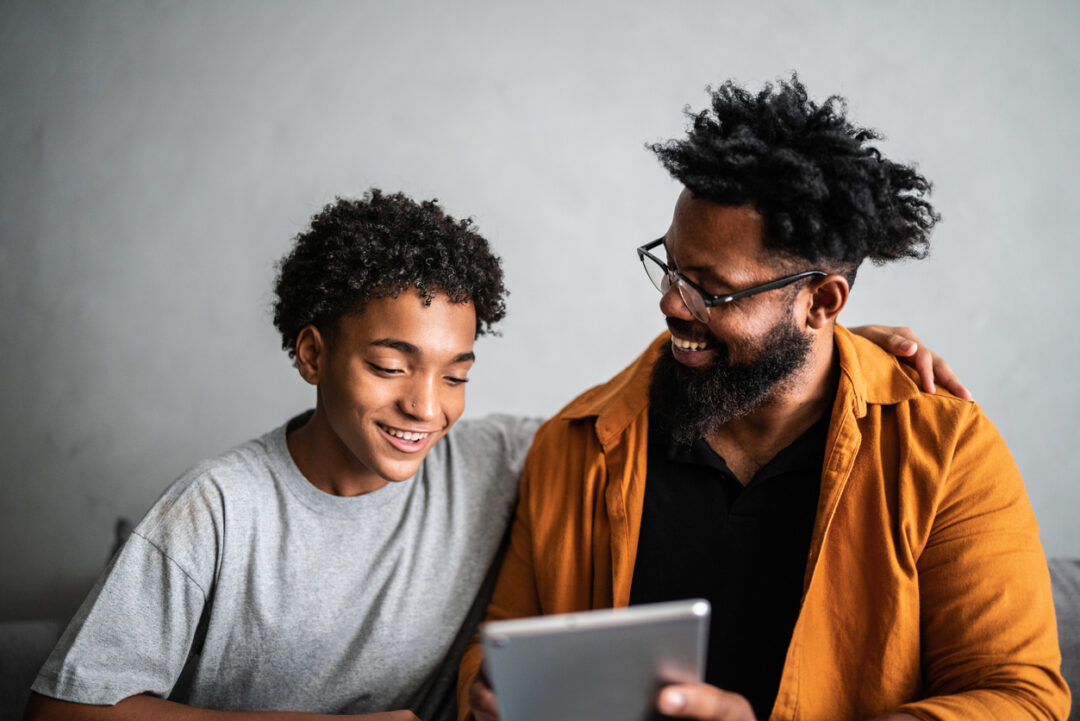 Happy father and son using digital tablet at home