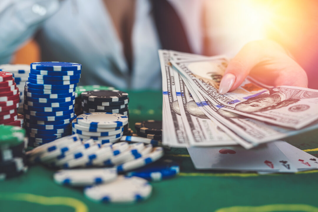 Greedy poker player after winning the game takes chips on a hundred dollar bill from the table.