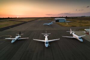 Four private jets parked on the runway, shot at sunset.