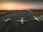Four private jets parked on the runway, shot at sunset.