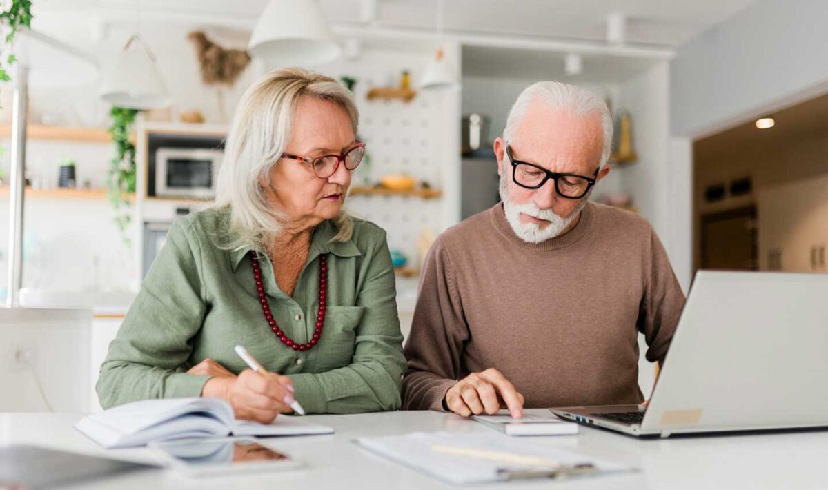 Retired couple looking at a computer and sheets of paper