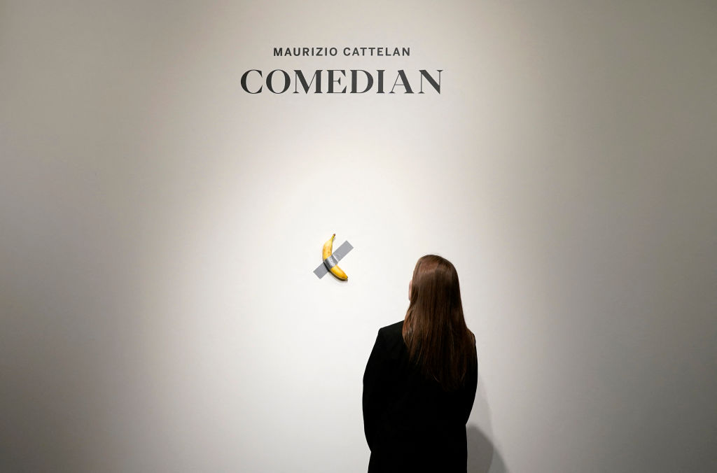 TOPSHOT - People look at Italian visual artist Maurizio Cattelan's duct-taped Banana entitled "Comedian," during a press preview at Sotheby's in New York, on October 25, 2024. The viral artwork was unveiled in 2019, and one of the artwork's three "editions" is going back on sale on November 20, 2024, and is estimated by Sotheby's to sell for between $1m and $1.5m. (Photo by TIMOTHY A. CLARY / AFP) / RESTRICTED TO EDITORIAL USE - MANDATORY MENTION OF THE ARTIST UPON PUBLICATION - TO ILLUSTRATE THE EVENT AS SPECIFIED IN THE CAPTION (Photo by TIMOTHY A. CLARY/AFP via Getty Images)