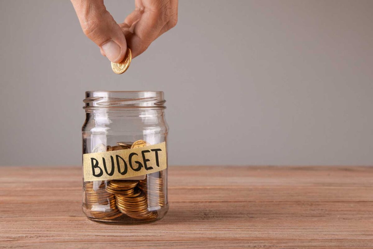 Man putting coin in a budgeting jar to save for the future