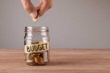 Man putting coin in a budgeting jar to save for the future