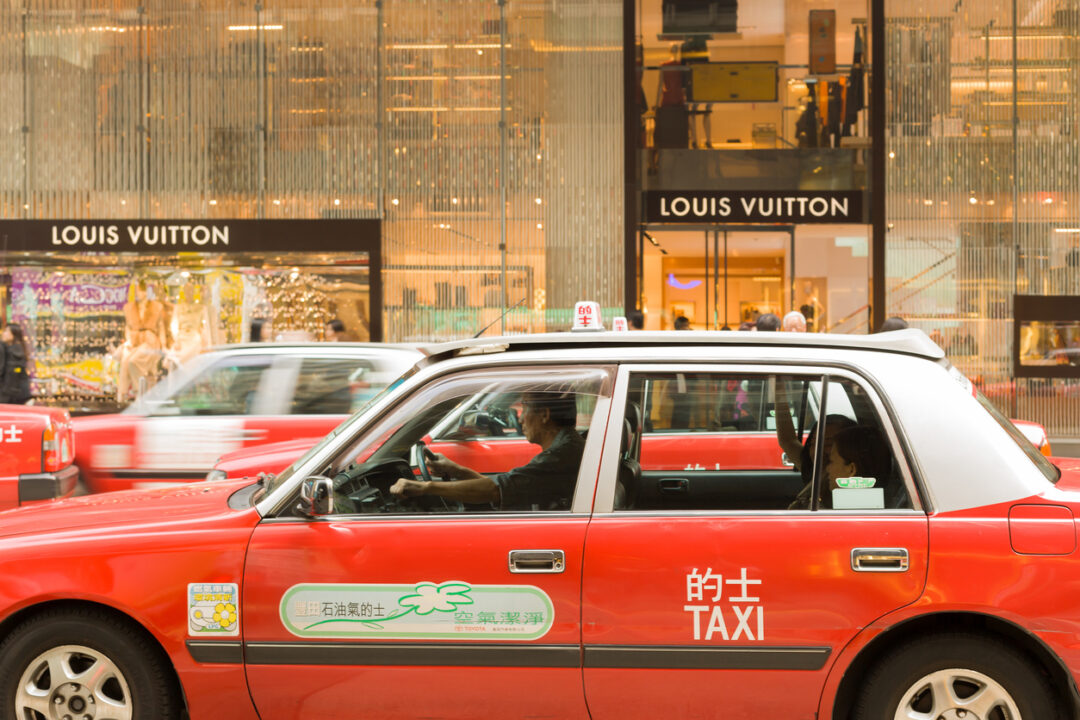 Hong Kong, Central district, China, Asia - November 14, 2008: Traditional red taxis in front of a Louis Vuitton store at Central district Hong Kong.