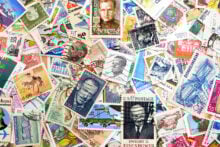 A colorful assortment of vintage postage stamps from various countries, featuring different designs, portraits, and themes. Some stamps display historical figures, landmarks, and intricate illustrations.