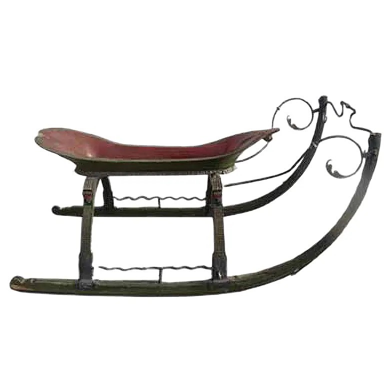 A vintage wooden sled with a curved front and intricate metalwork. The sled features a red seat and ornate metal accents along its frame, showcasing a classic design.