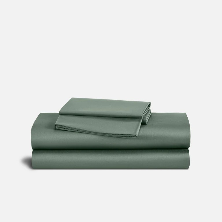 A neatly folded set of green bed sheets consisting of a flat sheet, a fitted sheet, and pillowcases, stacked on a white background.