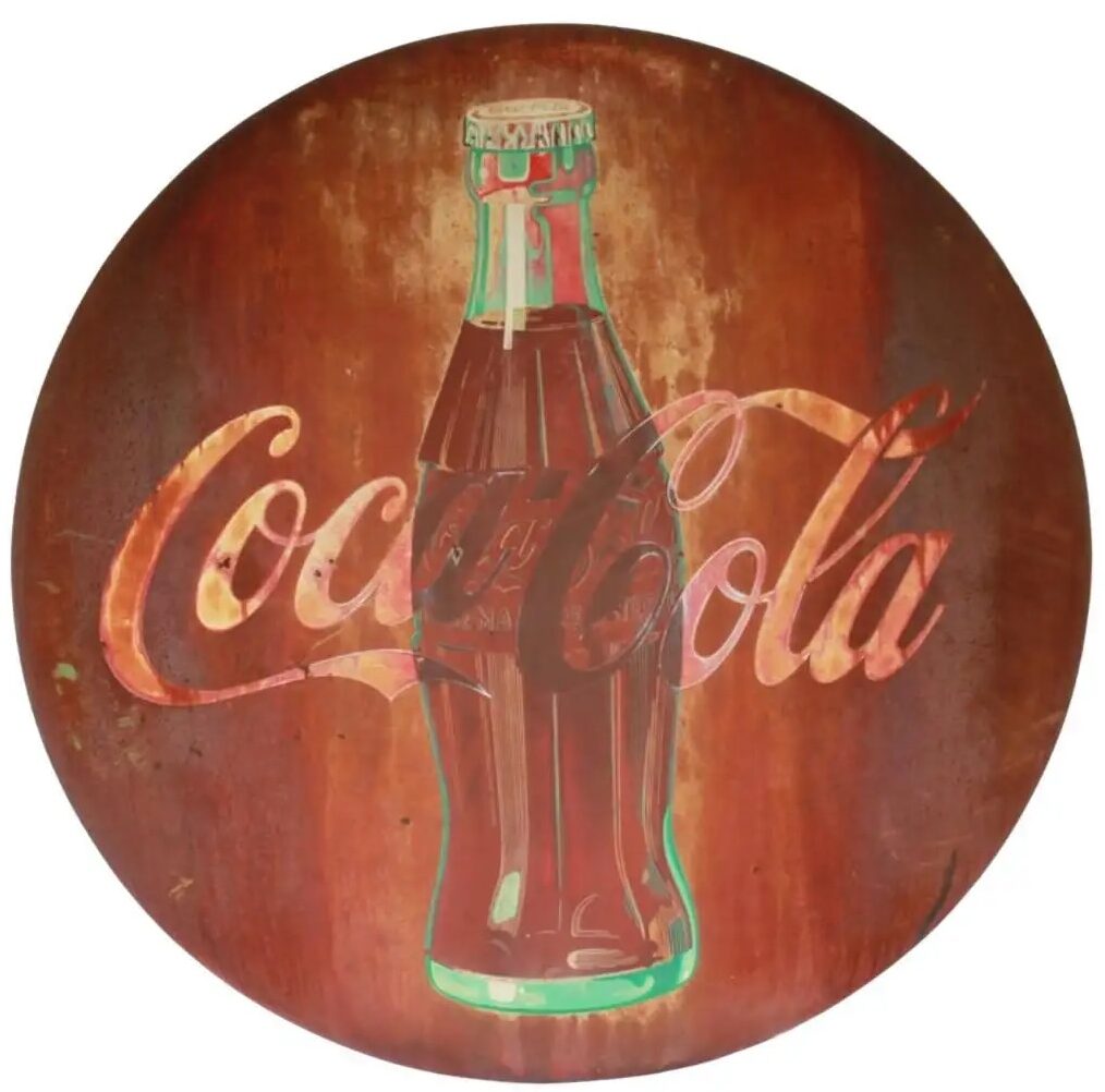 A vintage Coca-Cola sign featuring the classic glass bottle image and the Coke logo in red script. The sign has a rusted, weathered appearance, suggesting it is aged and worn.