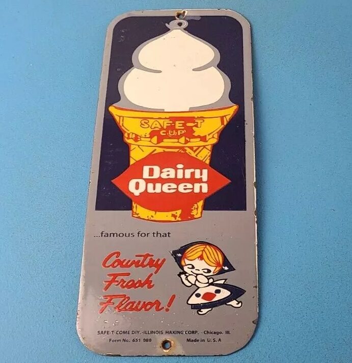 Vintage Dairy Queen sign featuring a soft serve ice cream cone illustration. It reads "Safe-T-Cup" and "Country Fresh Flavor!" with an image of a girl in a dress holding ice cream. Made by Safe-T-Cone Div. - Illinois Mfg. Corp., Chicago, USA.