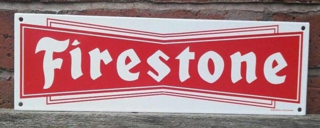 Red and white "Firestone" sign with bold lettering, mounted on a brick wall.