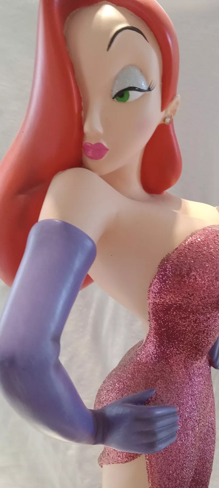 A figure of an animated character with long red hair, wearing a sparkly pink dress and purple gloves. The character has green eyeshadow and pink lipstick, striking a pose with one hand on their hip.