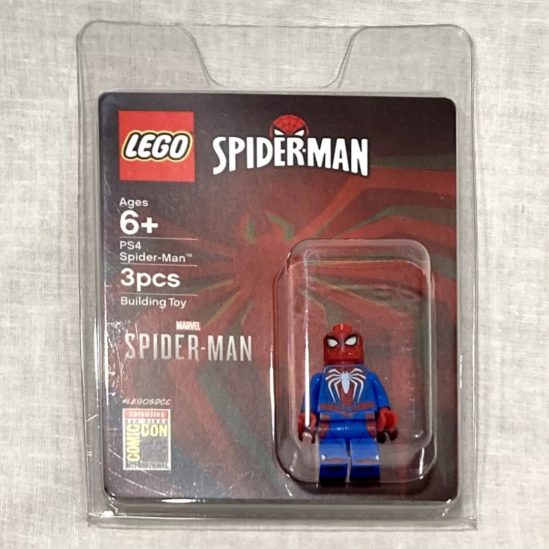 A packaged LEGO Spider-Man PS4 minifigure, recommended for ages 6 and up. The set contains 3 pieces and displays the Comic-Con logo. The packaging features a Spider-Man graphic background.