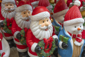 A festive display of Santa Claus and snowman figures crafted as charming blow molds. The Santas, in their red suits, hold holly wreaths, while the snowmen don red hats and carry green presents. Bright colors and cheerful expressions create a joyful holiday atmosphere.