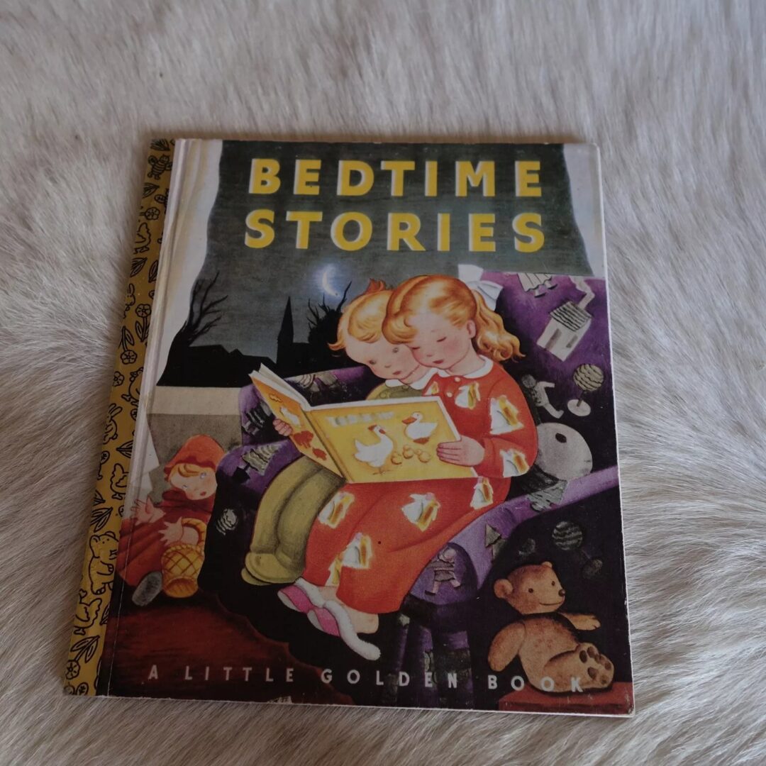 Cover of "Bedtime Stories," a Little Golden Book, featuring two children sitting on a chair. One child is reading a book, while the other looks on, surrounded by toys and a cozy setting.