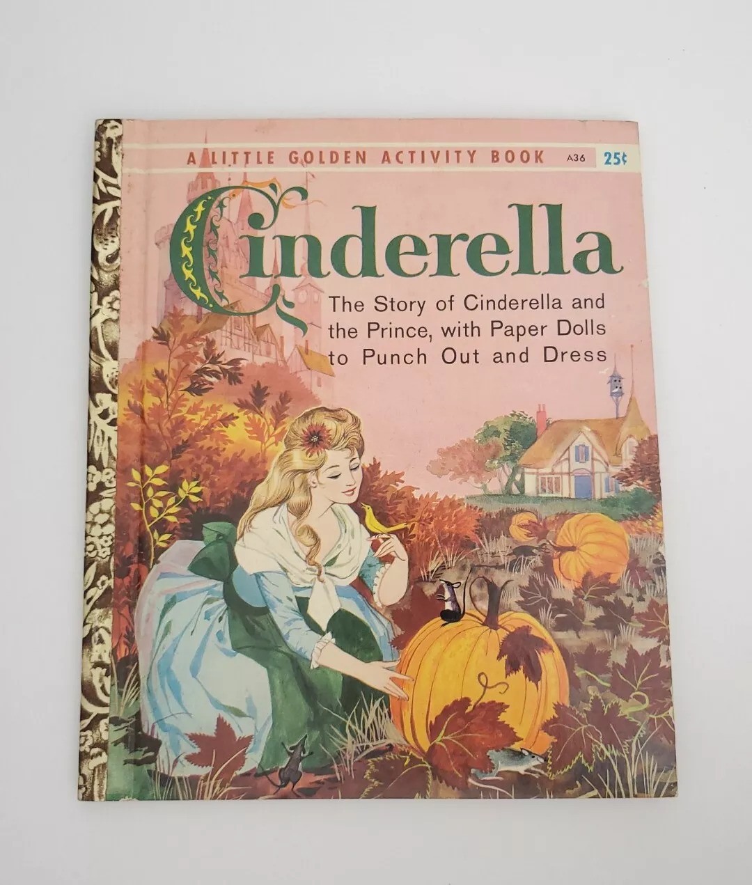 Vintage "Cinderella" activity book cover featuring an illustration of Cinderella in a garden wearing a dress, with a pumpkin nearby. Text reads: "The Story of Cinderella and the Prince, with Paper Dolls to Punch Out and Dress.