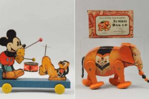 Two vintage tin toys: on the left, Mickey Mouse pulls Pluto on a wheeled platform with a drum; on the right, an orange elephant with a raised trunk stands by a "Jumbo Bak-Up" box.