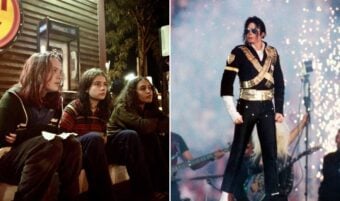 Three people sit together on a curb at night, looking forward. Next to them, a performer in a striking black and gold outfit stands confidently on stage with pyrotechnics and musicians in the background.