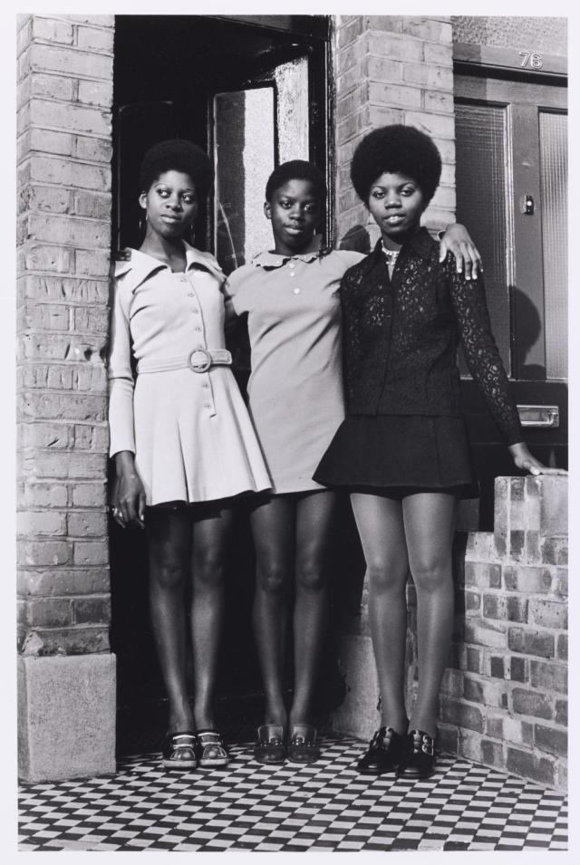 three sisters standing together by a brick building in london during the 1970s