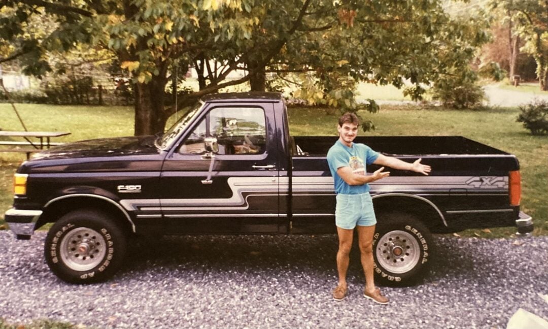 teenager giving a thumbs up near a black 1991 F-150 pickup truck