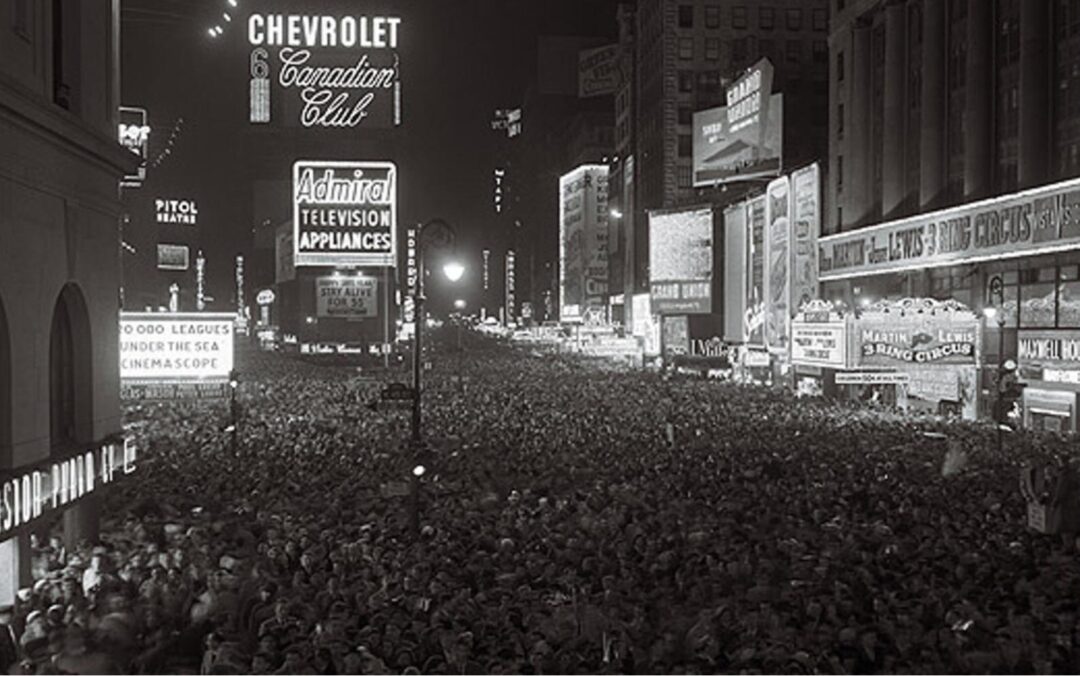A large crowd fills Times Square at night, surrounded by bright, illuminated billboards and signs, including Chevrolet, Canadian Club, and Admiral Television Appliances.
