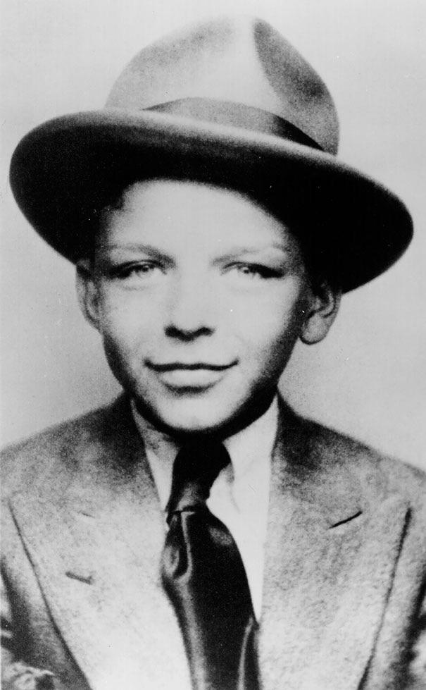Black and white portrait of a young boy wearing a suit, tie, and wide-brimmed hat, looking slightly to the side with a faint smile.